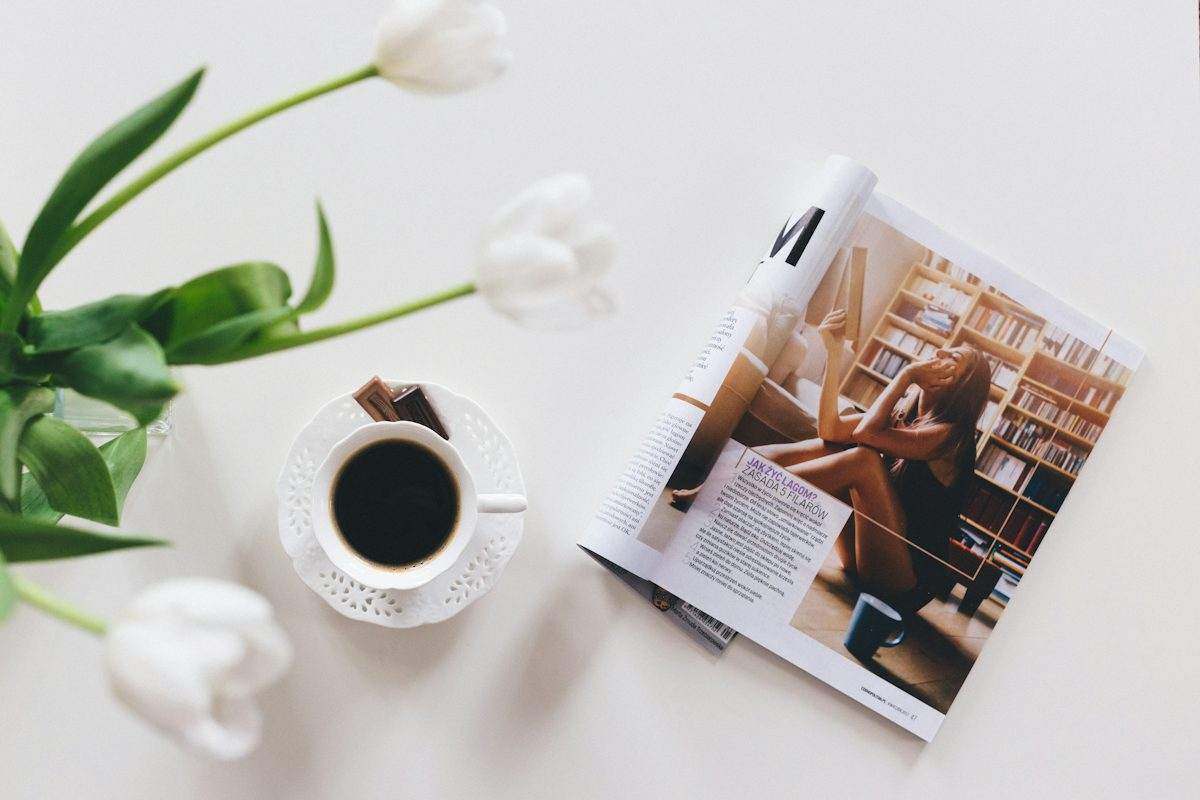 A magazine open beside coffee and flowers